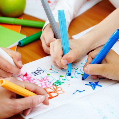 Close-up of human hands drawing with colorful highlighters